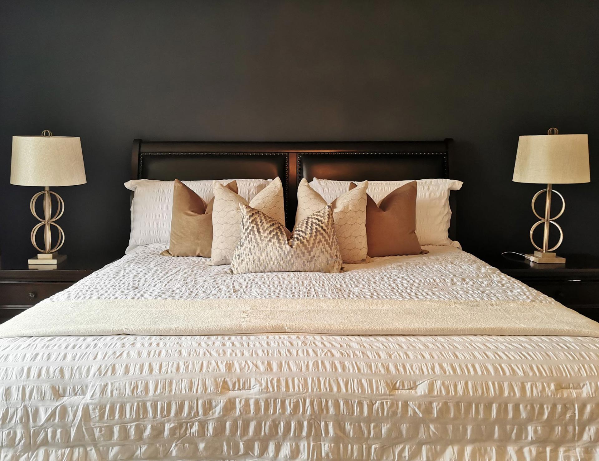 Bed set up by a home staging firm with decorative pillows and lamps